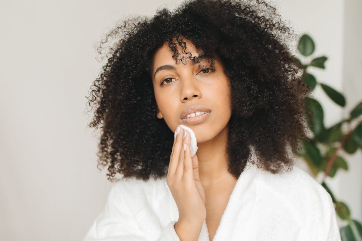Capture of a woman gently cleansing her face with a cotton pad indoors.
